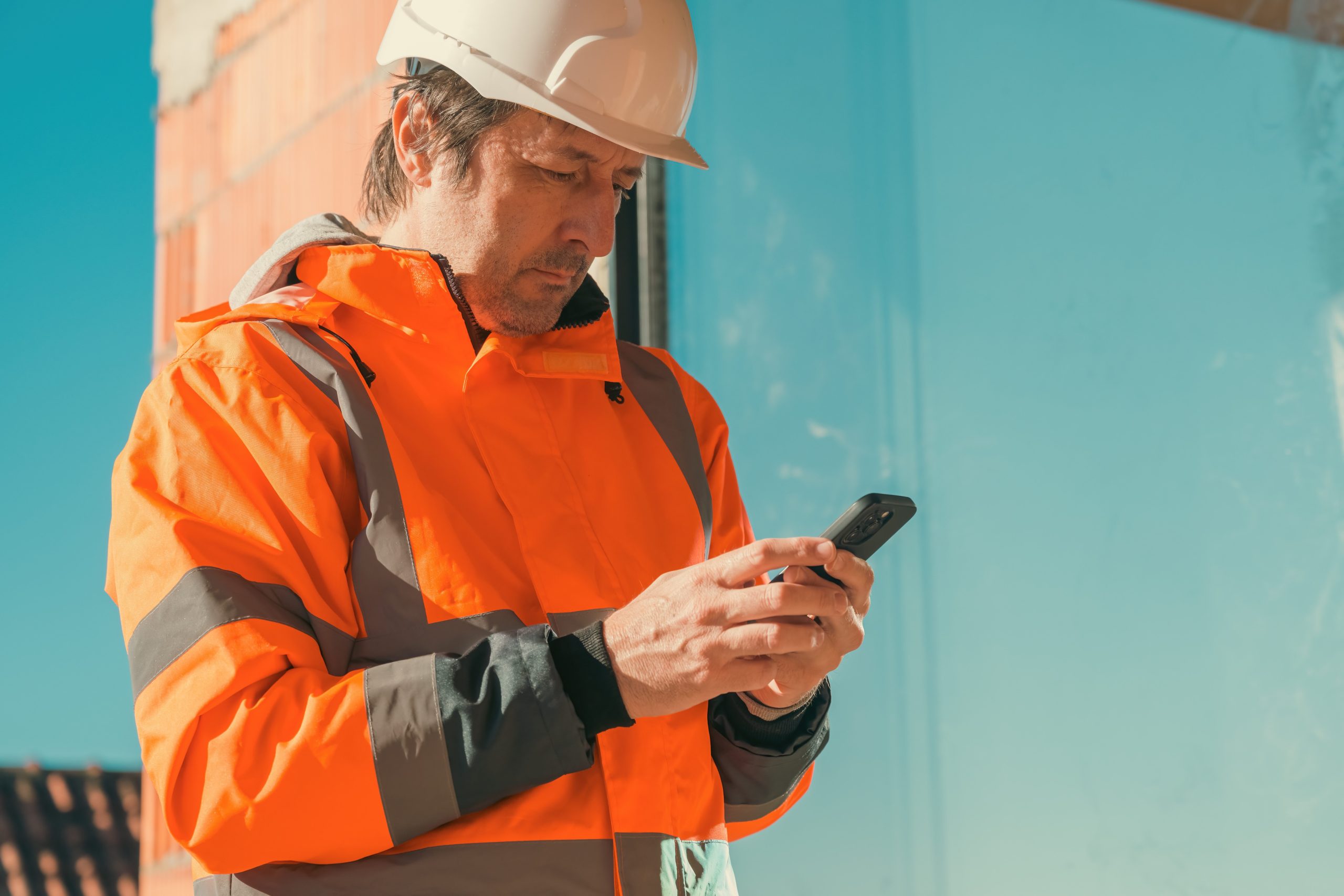 Construction worker completing a CDM compliance checklist on a mobile phone on site