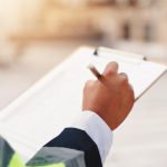 Construction worker in a hi-vis jacket completing a site safety inspection checklist on a clipboard