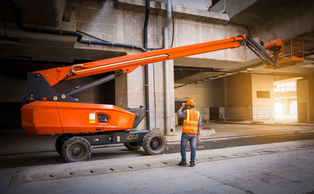 Operator carrying out a MEWP pre-use inspection on a boom lift before use on a construction site