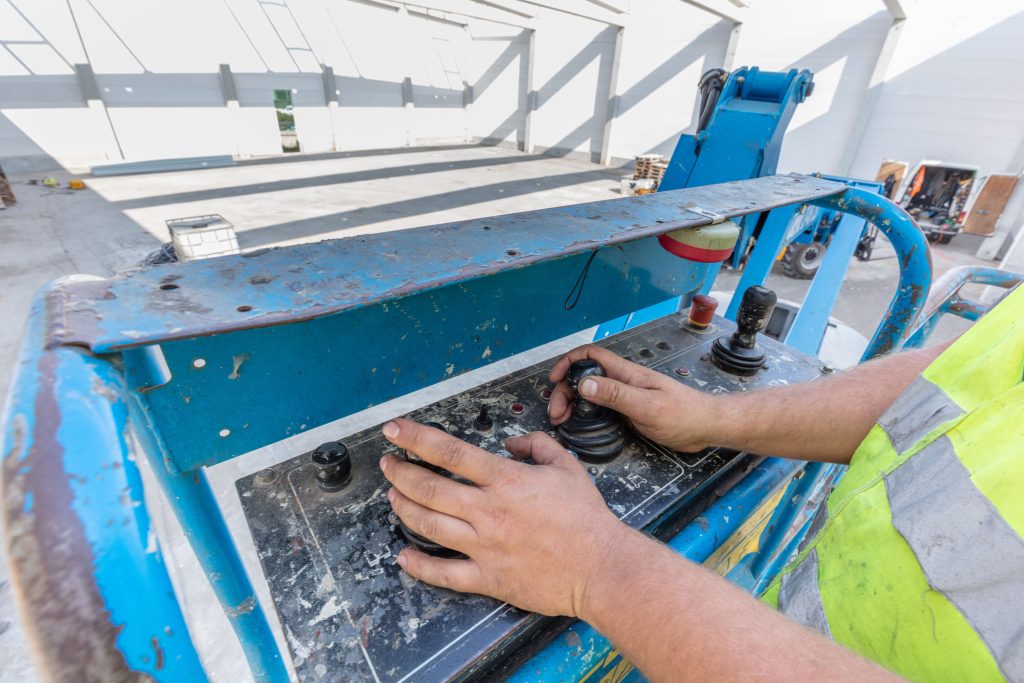 Operator testing scissor lift platform controls during a MEWP functional check